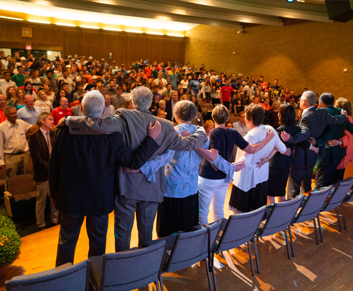 Falk faculty, staff and new students sing the Alma Mater in Grant Auditorium at the new student welcome meeting.