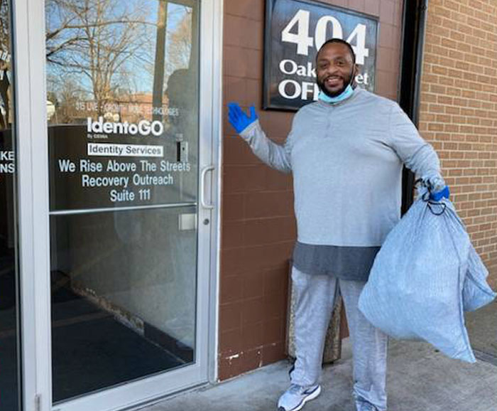 A man is at a door with a bag of donations