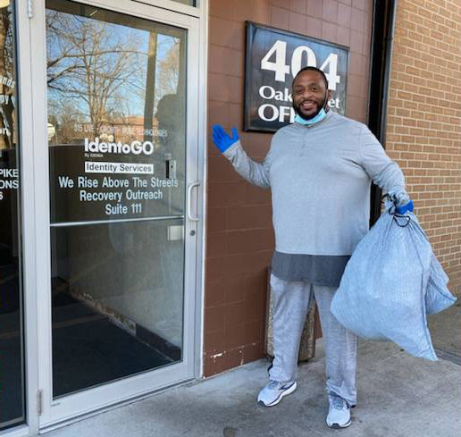 A man is at a door with a bag of donations