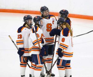 Allie Munroe and fellow hockey teammates discuss on the ice