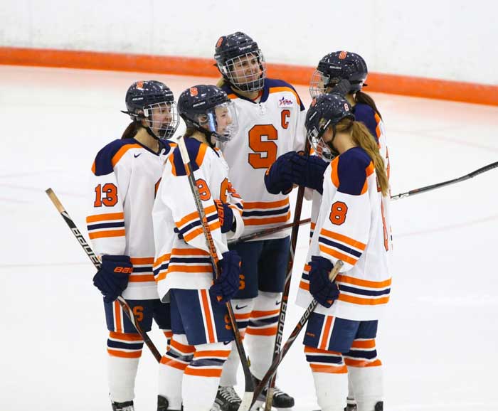 Allie Munroe and fellow hockey teammates discuss on the ice