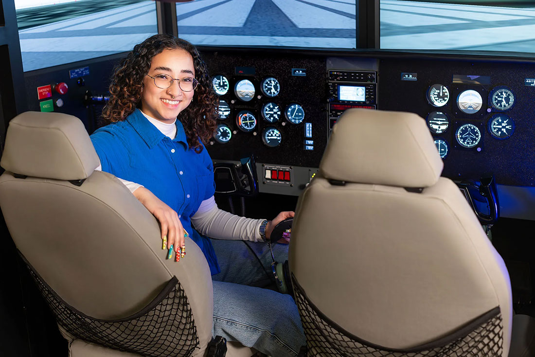 female student Allyson Almedia sitting in the cockpit of a plane