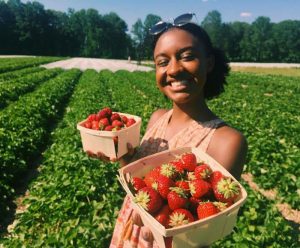Ashia Aubourg holds picked strawberries in a field