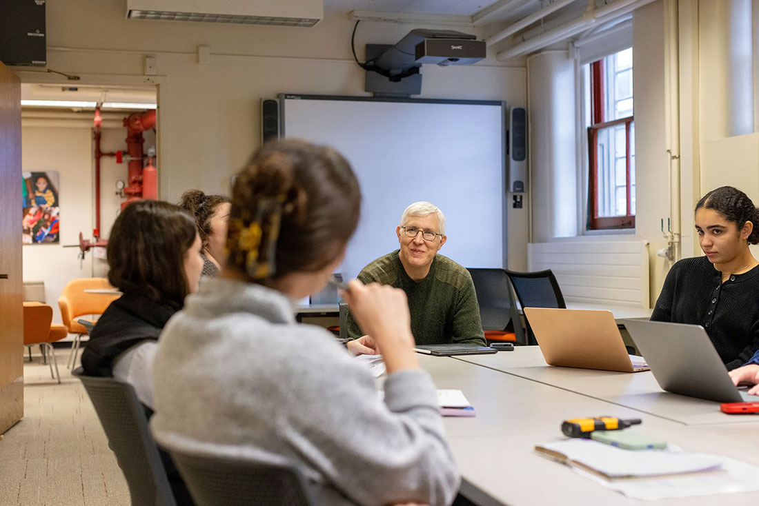 Male professor meets with students taking his course