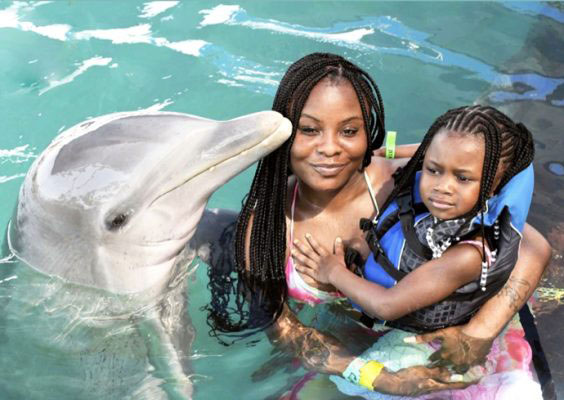Benetta Dousuah and her daughter pose with a dolphin