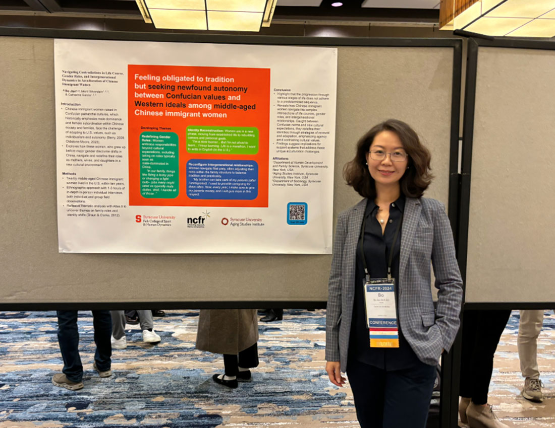 Bo Jian stands next to a research poster at a conference