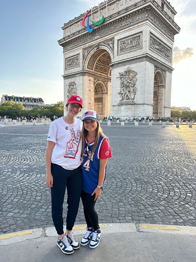 Two women standing in front of the Arc for both the Olympic and Paralympic games