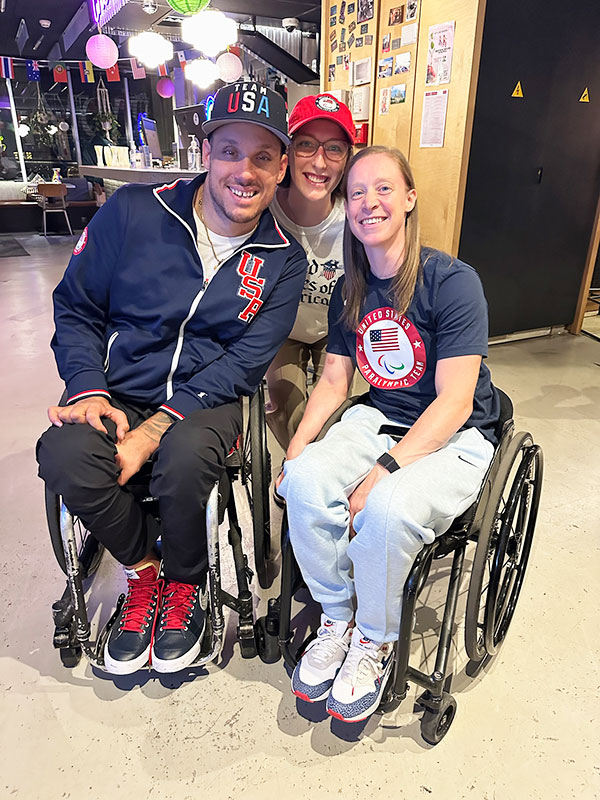 One male and one female rugby wheelchair competitors posing with another female