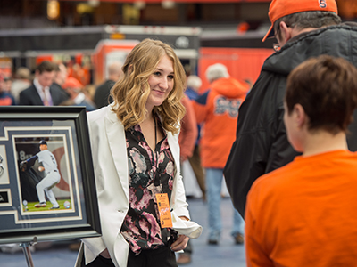 A student stands next to a framed photo at an auction