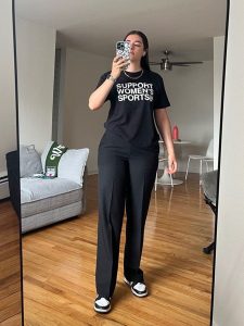 young woman in front of mirror taking selfie of her tshirt that reads support women's sports