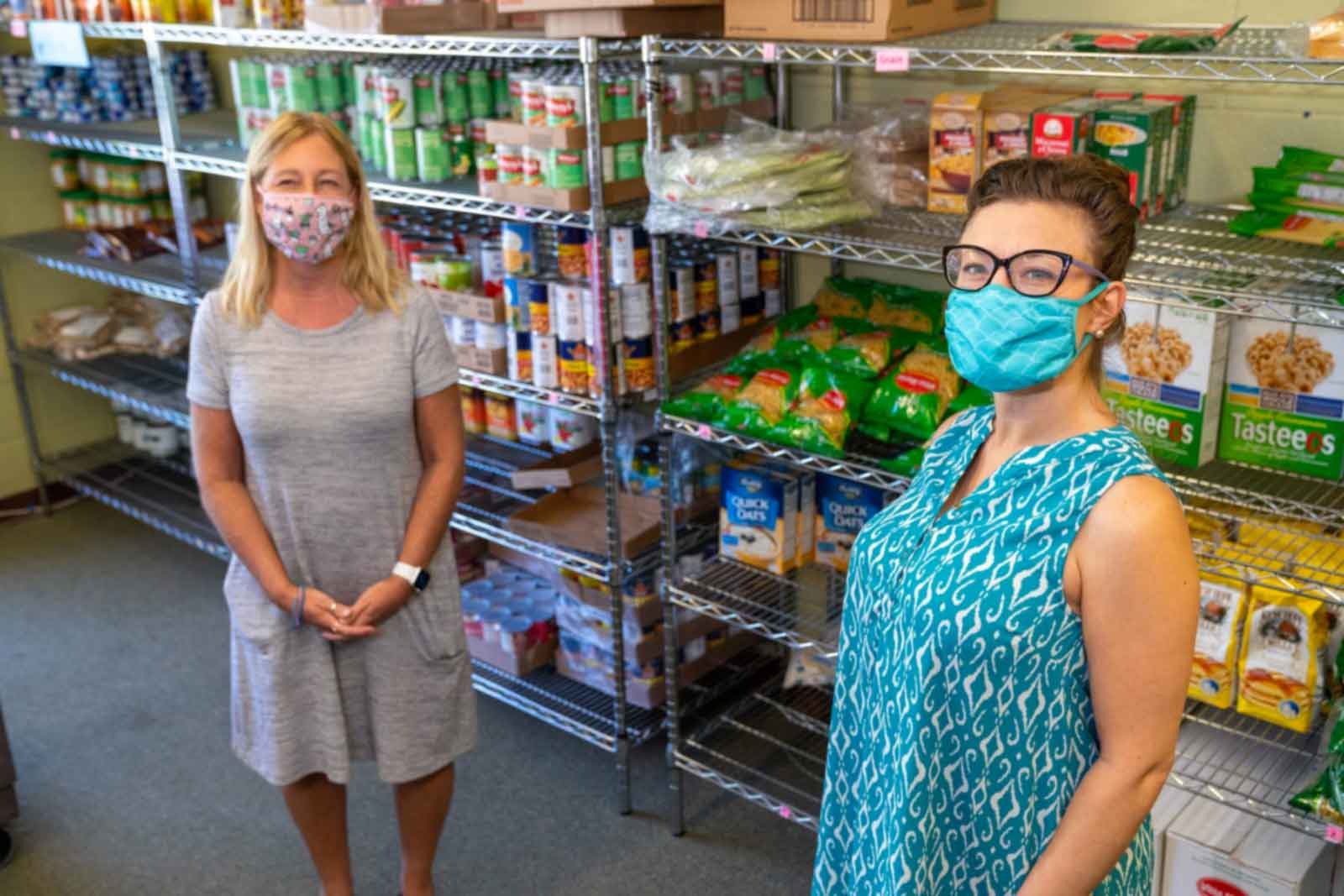 Two women stand in a food pantry isle