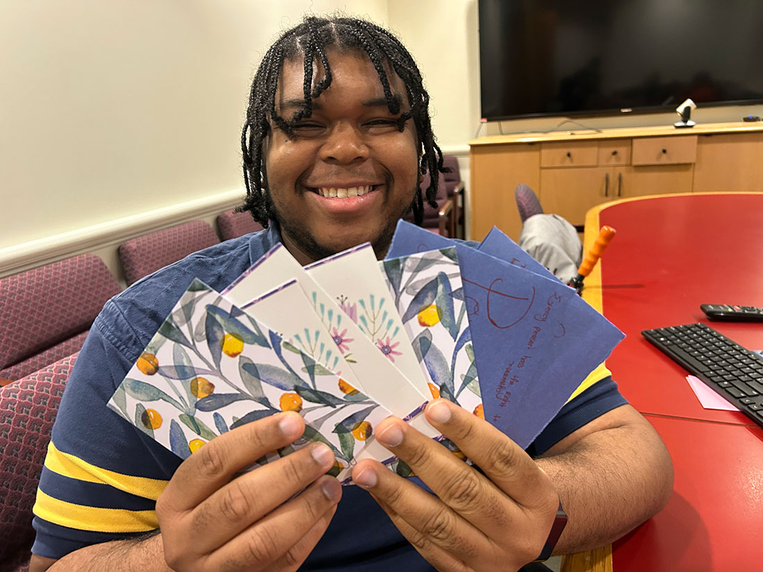 Social Work graduate student holding cards in his hand that will be distributed to clients.