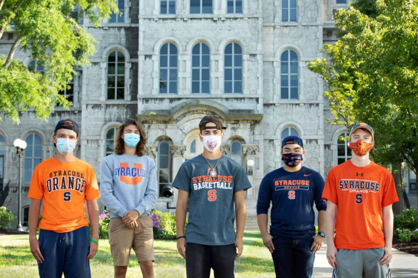 5 masked individuals are standing in front of the hall of languages