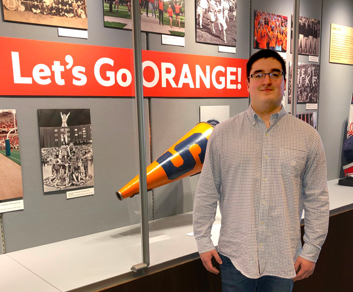Student David Ross stands in front of a display case at Syracuse University Archives.