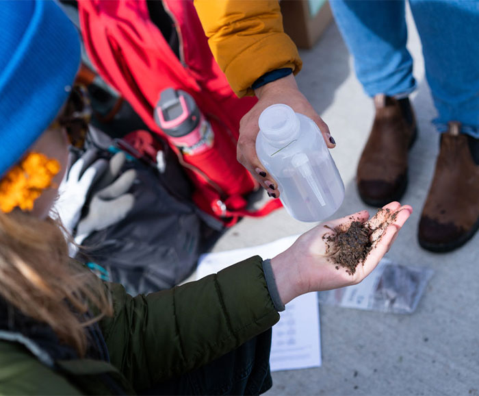 Student holds dirt in hand while others watch