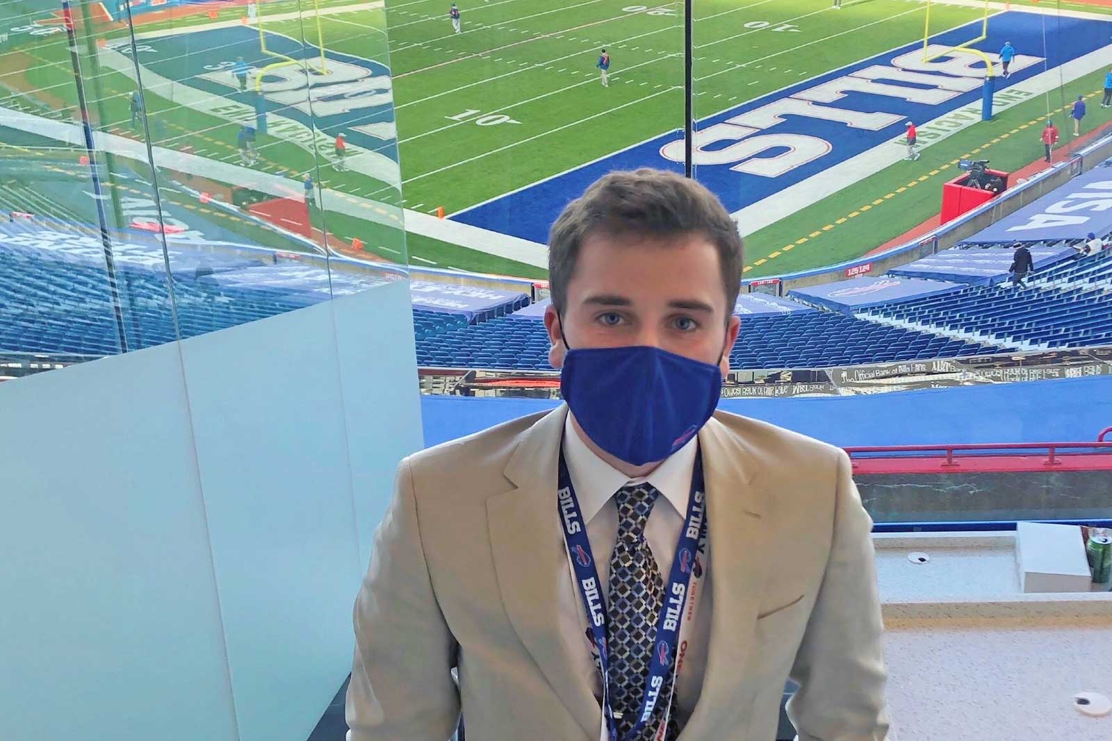 Drew stands in a stadium box overlooking a football field