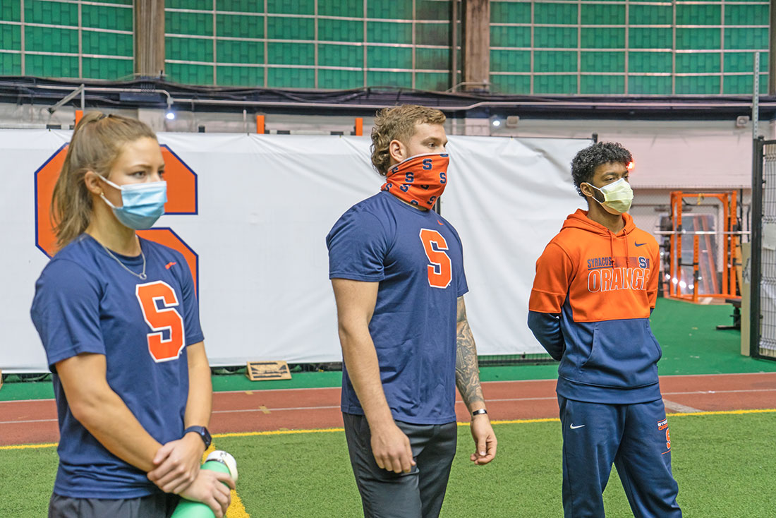 three students stand in an indoor field