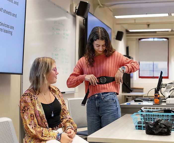 Student putting on electronic monitoring device around chest