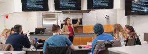 A professor addresses a class in a cooking food laboratory classroom