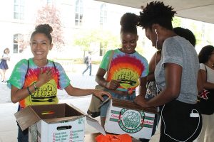 Three students organize fresh produce into boxes