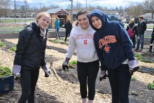 Three female students are posed inside an urban garden under construction