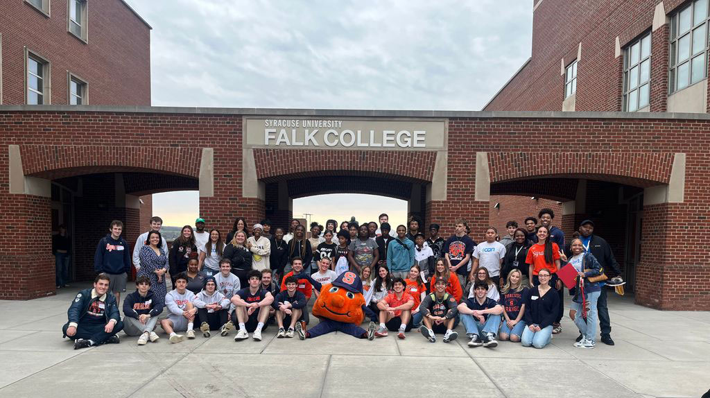 Students from Utica take a group photo in front of Falk College with Otto front and center
