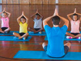 School children and teacher meditating during a yoga class in a school gym