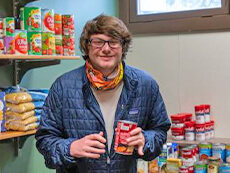 Tucker Kopp holding canned foods available in the SU Sustainability Office pantry.
