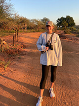 Nicole poses for a photo in South Africa. A giraffe is visible in the background.