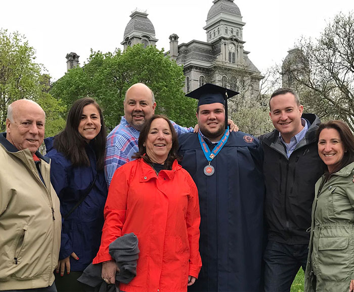 7 people standing together in front of campus builsding