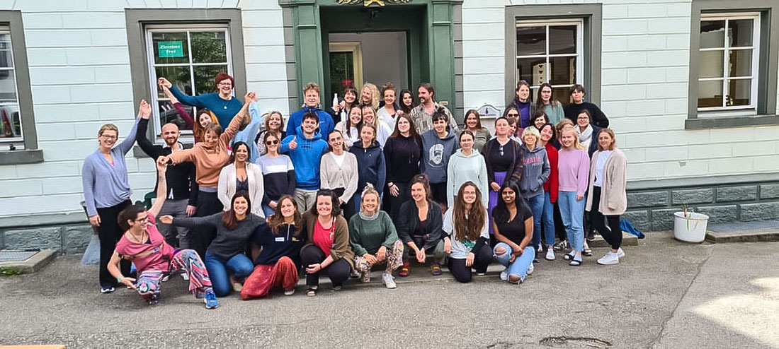 46 persons from diverse universities standing in front of a brick building.