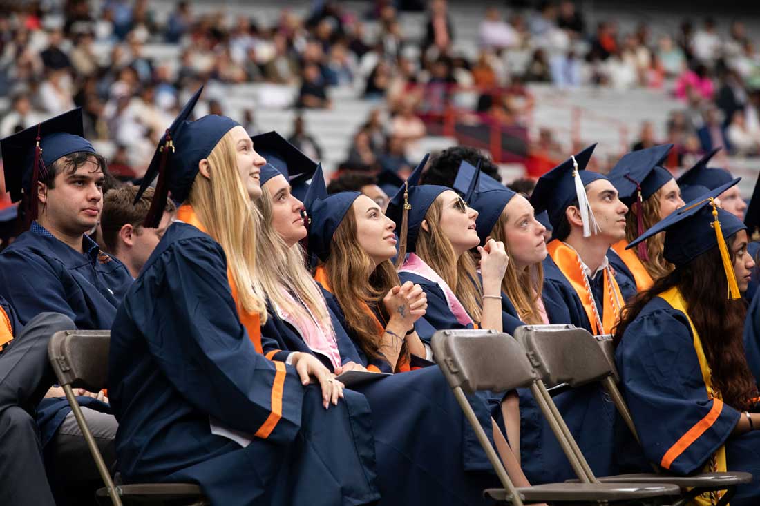 Students in a graduation ceremony sitting in folding chairs