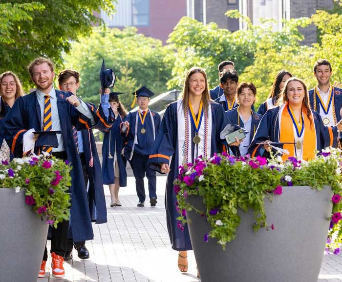 Graduates are walking down a path in Syracuse University campus