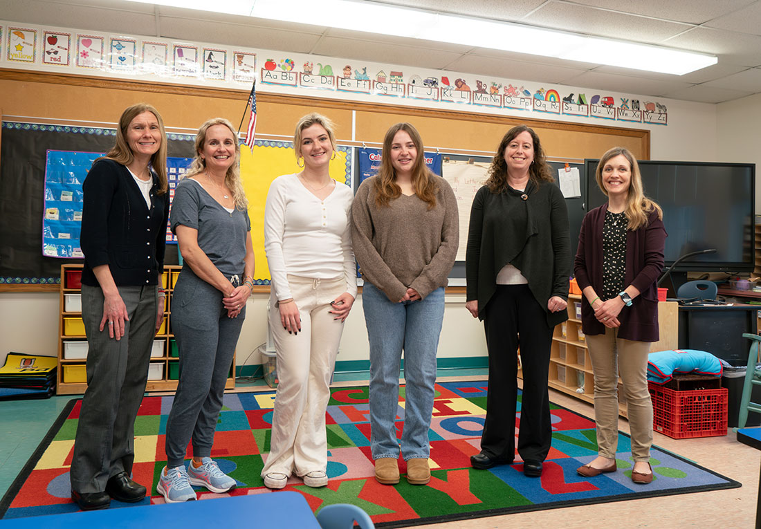 6 female teachers standing in a row in the front of a classroom