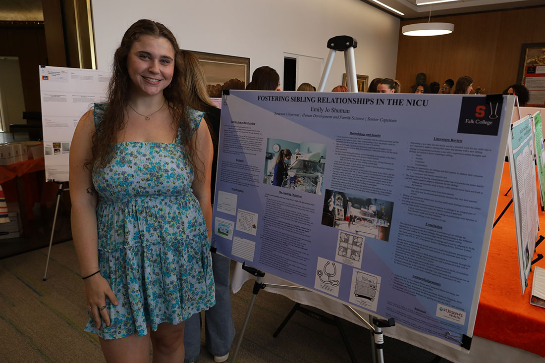 Female student standing next to poster she is presenting