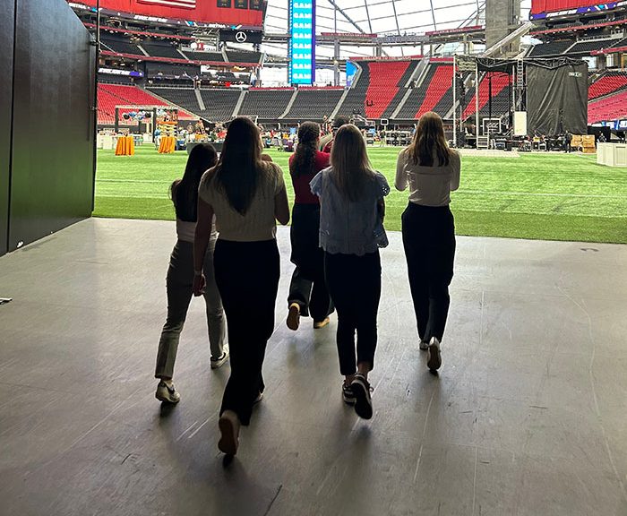 five females viewed from behind walking out onto athletic field