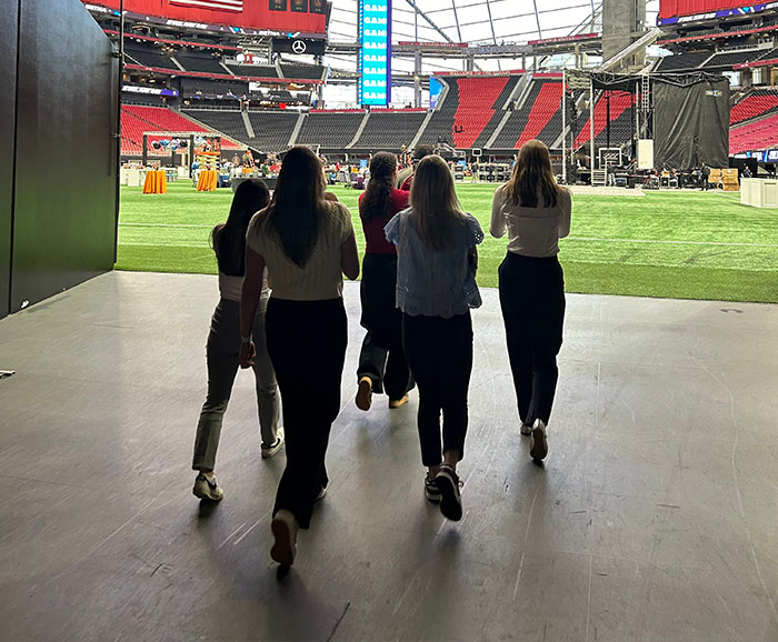 five females viewed from behind walking out onto athletic field
