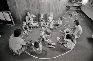 children and adults sit on the floor around a circle