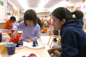 A student sits with a child who is playing