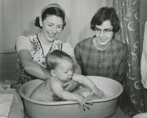 A 1950s photo showing two students are giving a baby a bath