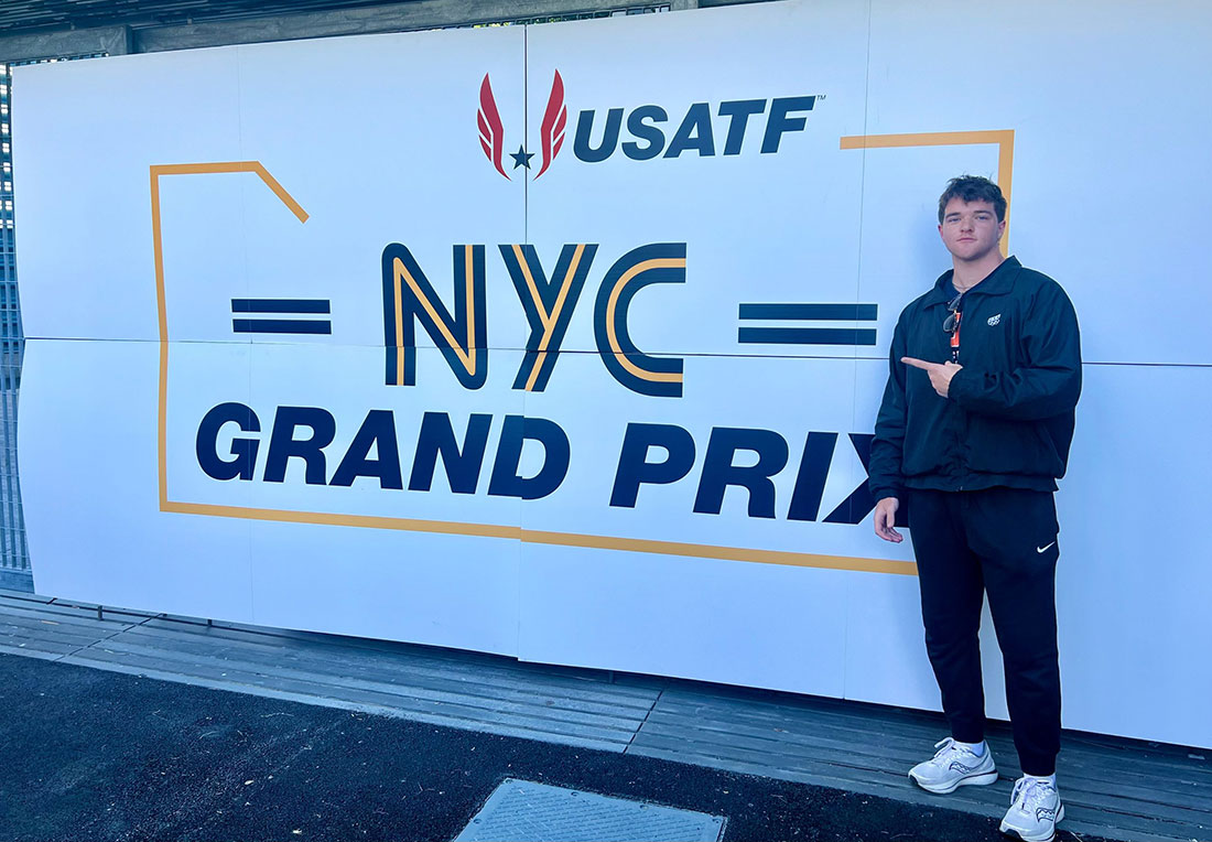 Dan Griffiths standing infront of a USATF NYC Grand Prix sign
