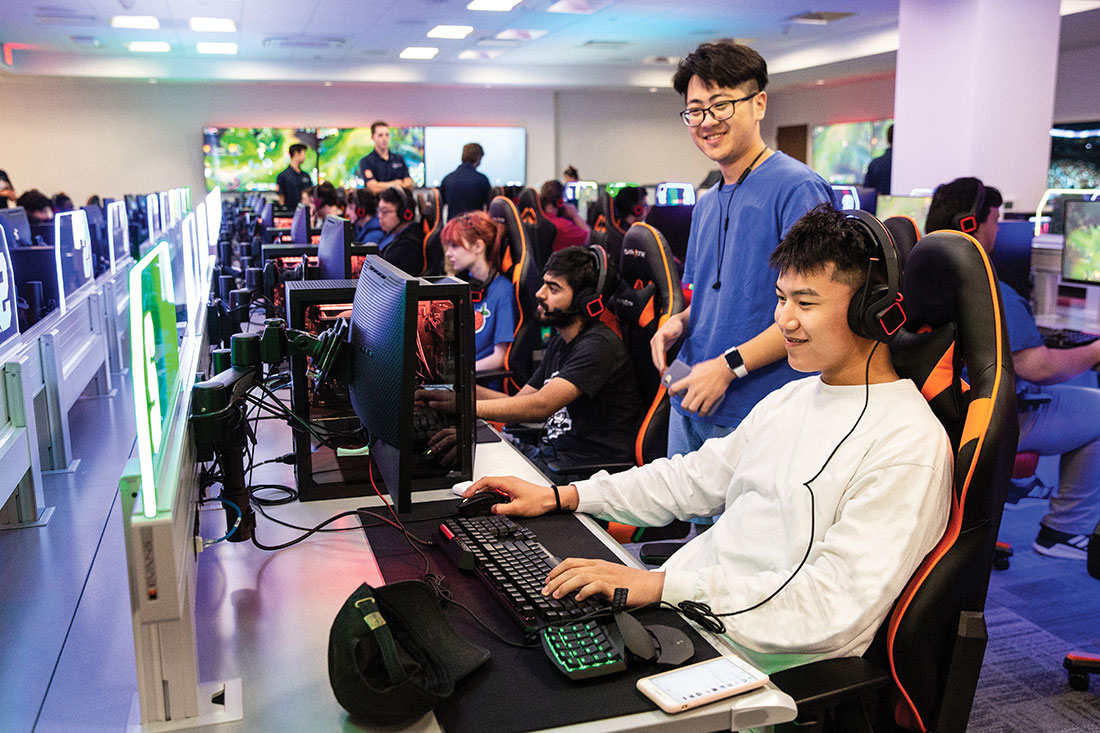 Students sitting at gaming stations wearing headphones