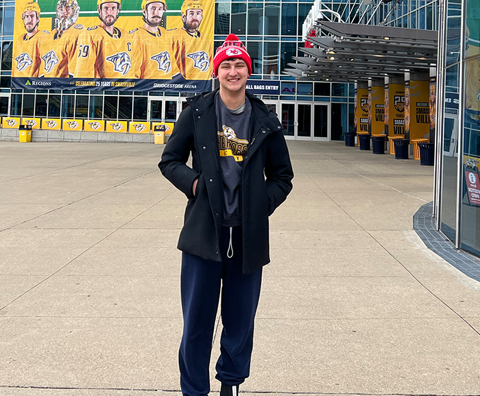 Male student standing outside of athletic stadium.