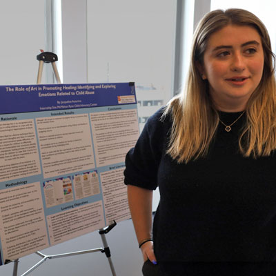 Jacqueline stands next to a research poster