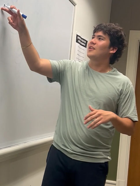 Jarrett Markman writing on a white board with a marker