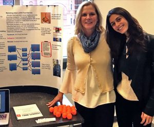 Kara Danziger poses beside her research poster on SU Food Services