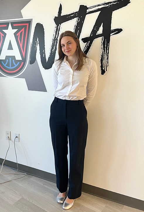 female student wearing black pants and white shirt, long brown hair