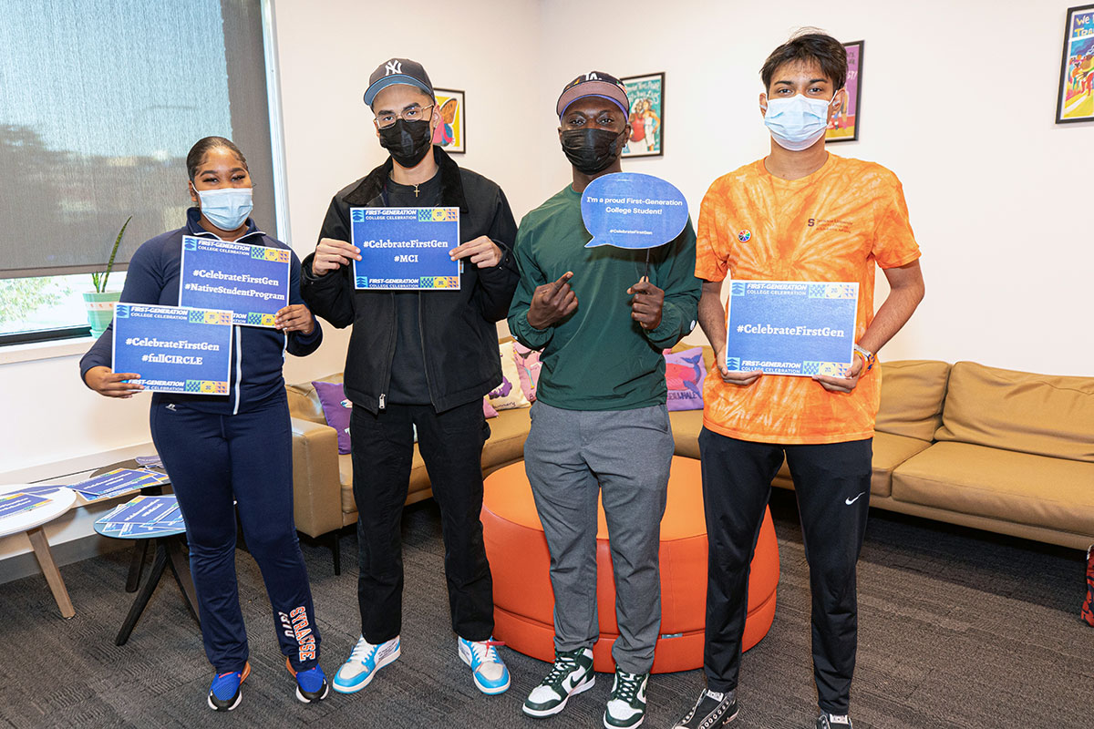 Four students are posed holding signs saying first generation