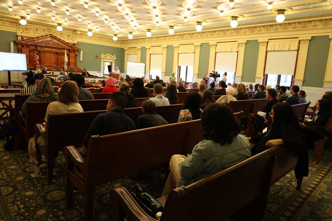 A courtroom full of people listen to a presenter