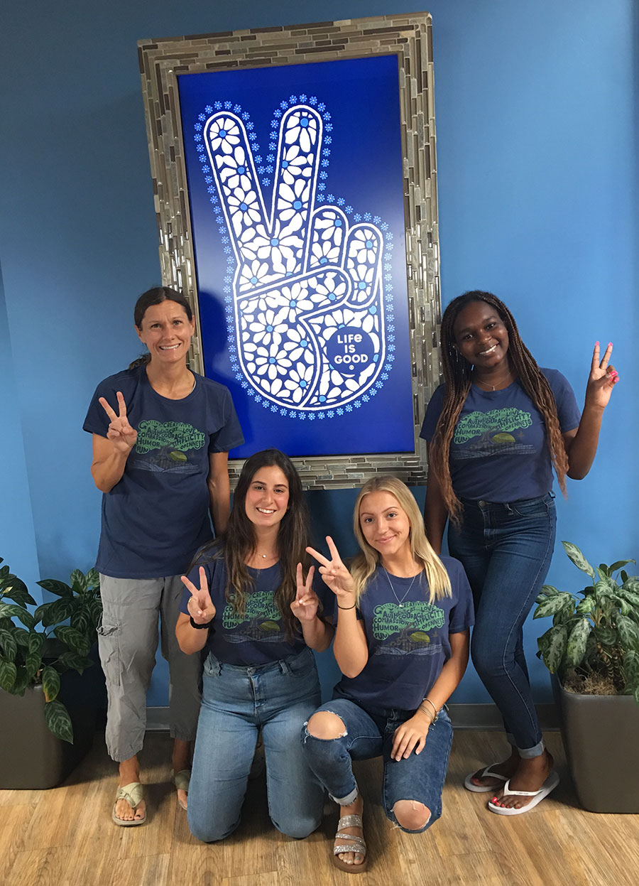 three students and professor pose with Life is Good logo